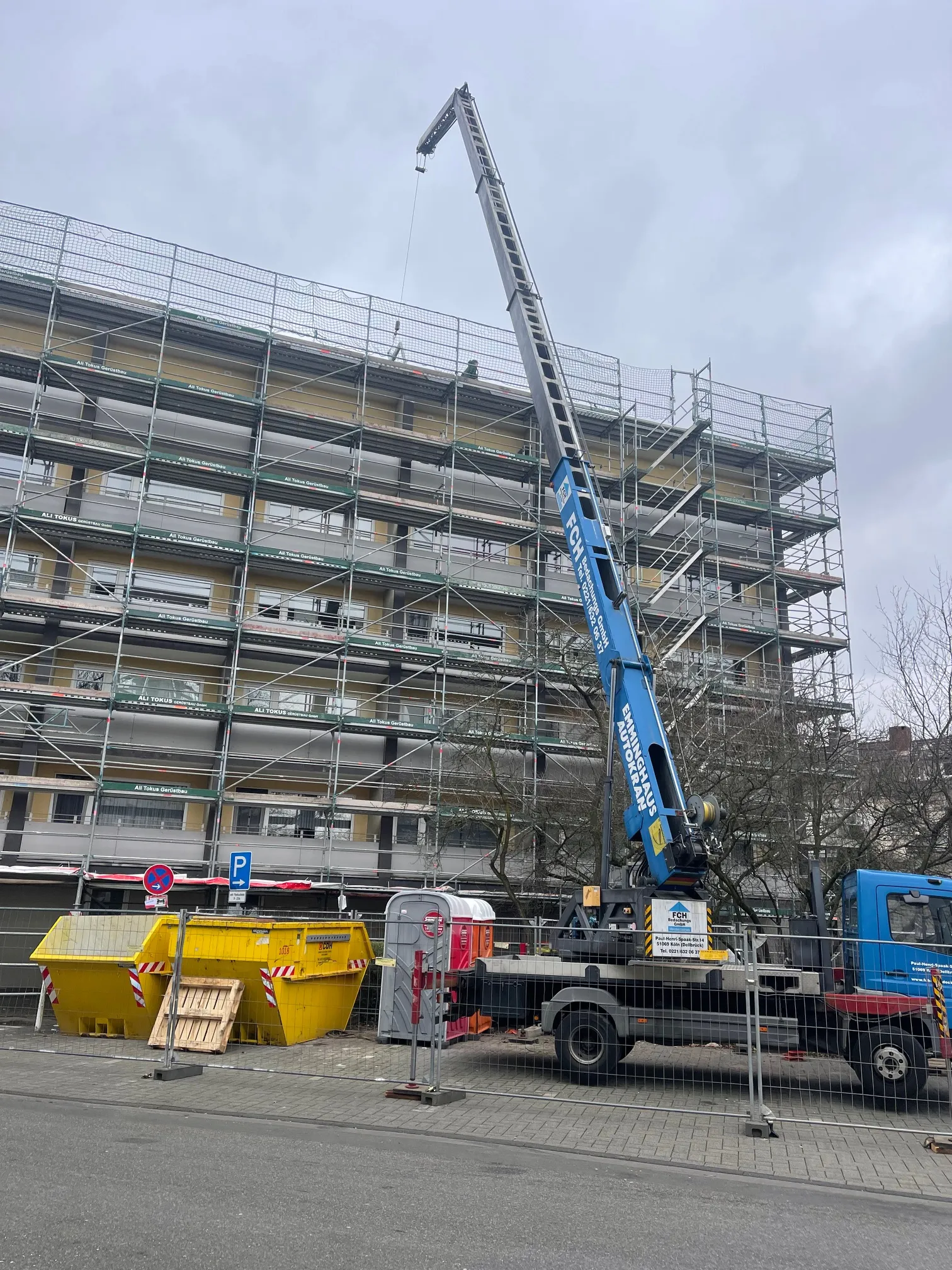 FCH-Kran vor einem eingerüsteten Mehrfamilienhaus.